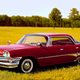 A red Dodge Dart parked in a field.
